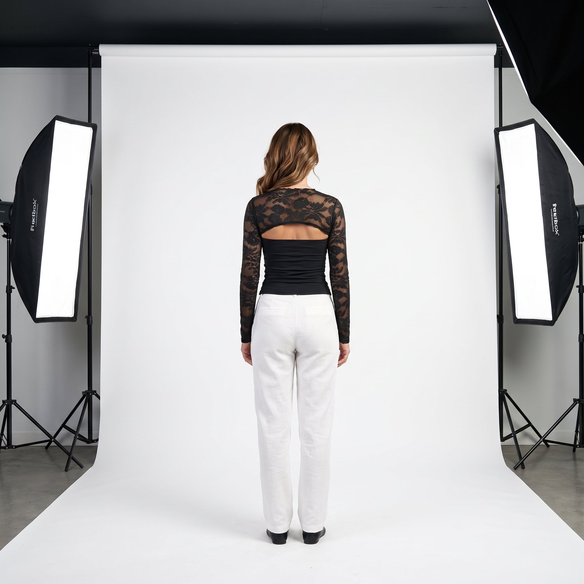 Top negro de encaje floral con panel liso y manga larga transparente, escote tipo barco