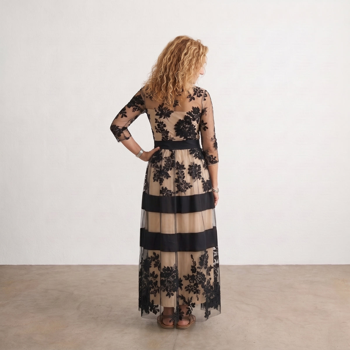 Vestido largo de tul negro con flores, franjas beige y azul marino, vista trasera.