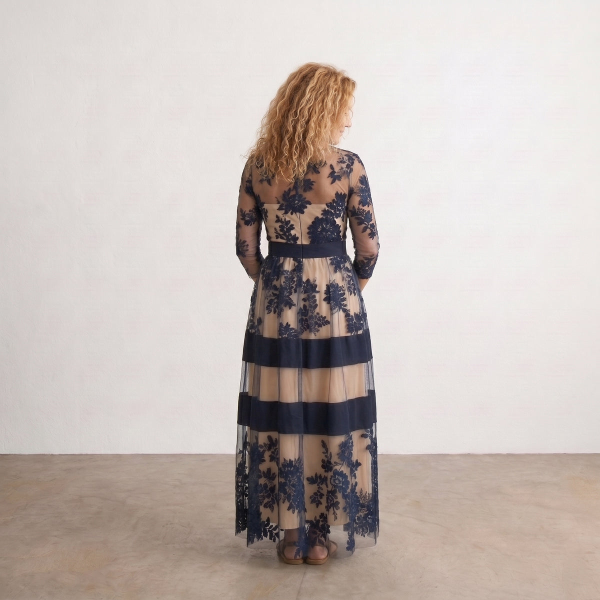 Vestido largo de tul negro con flores y franjas beige y azul marino, mangas tres cuartos.