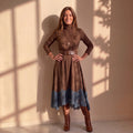 Vestido marrón oscuro de cuello alto con cinturón y bajo con encaje azul, frontal.
