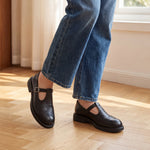 Mocasín Louisa™ de cuero negro con hebilla, puesto con jeans