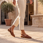 Mocasines Monica marrones trenzados, puestos con pantalón claro, suela plana