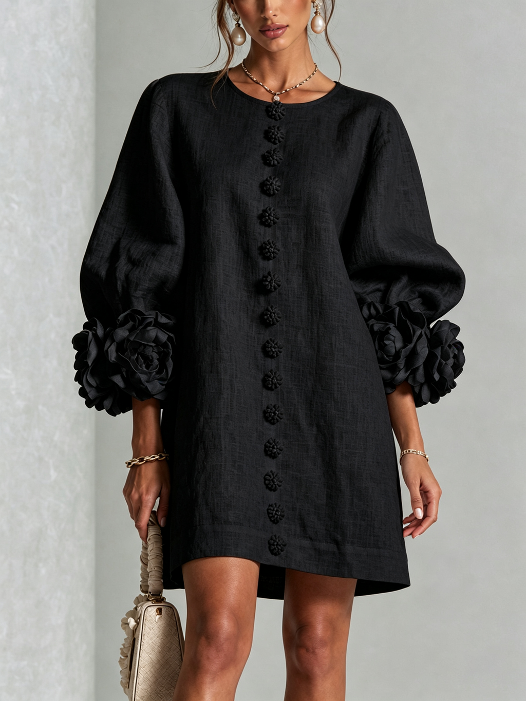 Minivestido negro con botones al frente y mangas abullonadas con flores voluminosas.