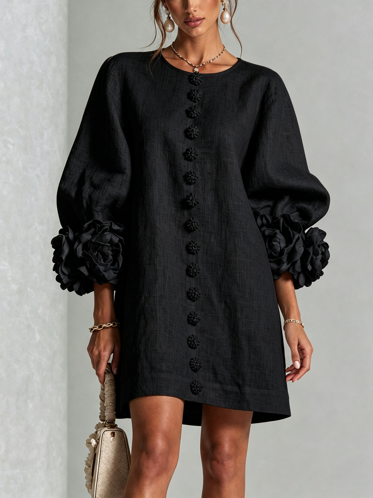 Minivestido negro con botones al frente y mangas abullonadas con flores voluminosas.