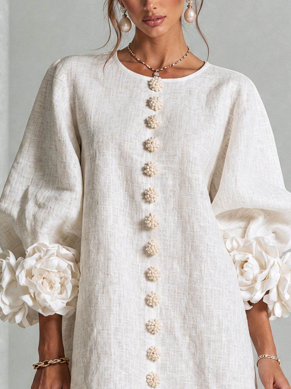 Vestido blanco de lino con botones florales dorados al centro y mangas abullonadas