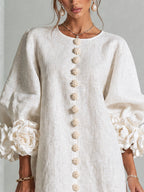 Vestido blanco de lino con botones florales dorados al centro y mangas abullonadas