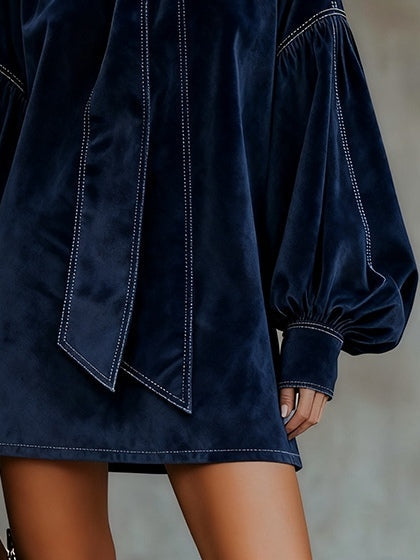 Vestido azul oscuro con lazo delantero y dobladillo recto; mangas globo abullonadas