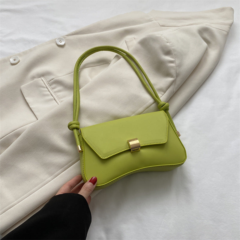 Bolso mini verde lima con solapa, hebilla dorada y asas trenzadas ajustables.