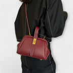 Bolso de cuero burdeos con cremallera central y asa superior