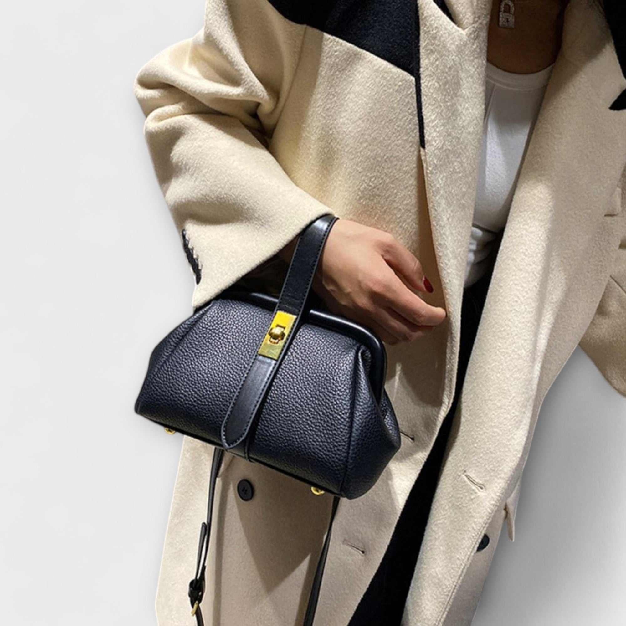 Bolso Maelis azul marino de piel con asa superior y correa ajustable, cierre metálico dorado.