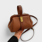 Bolso de cuero marrón con asa superior y correa cruzada