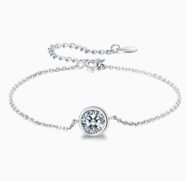 Pulsera tipo solitario de plata con dije circular y piedra transparente engastada.