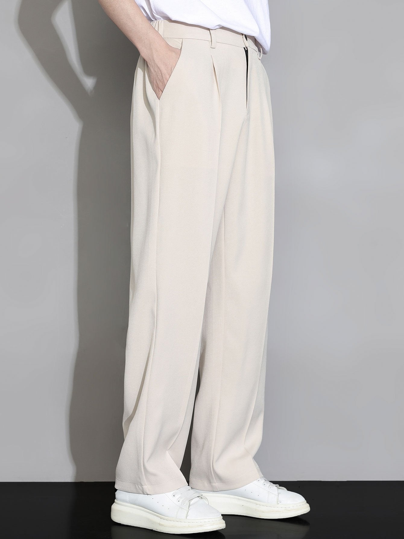 Pantalón recto relajado beige claro con cintura y bolsillos laterales; pernera amplia.