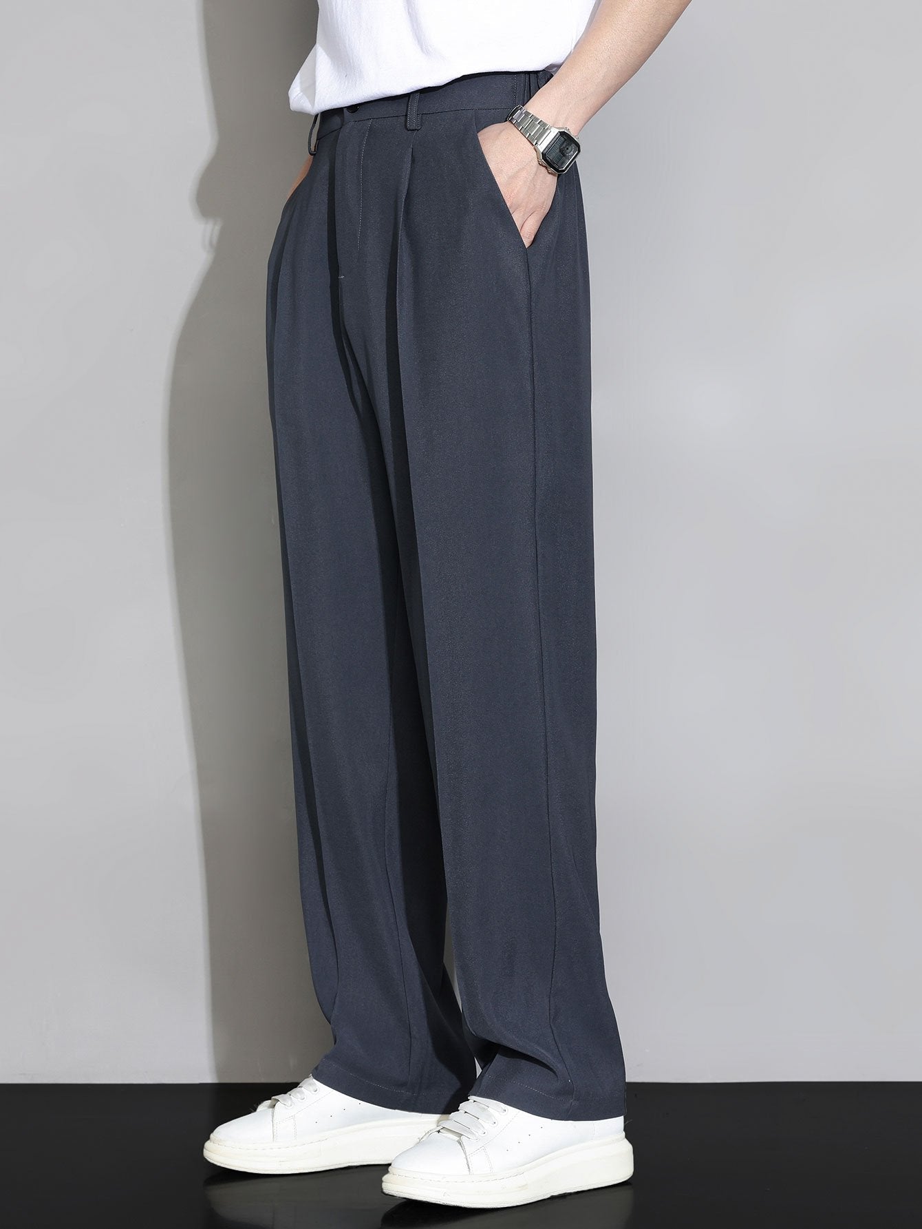 Pantalón recto relajado gris oscuro, cintura ajustada y bolsillos laterales; caída suelta.