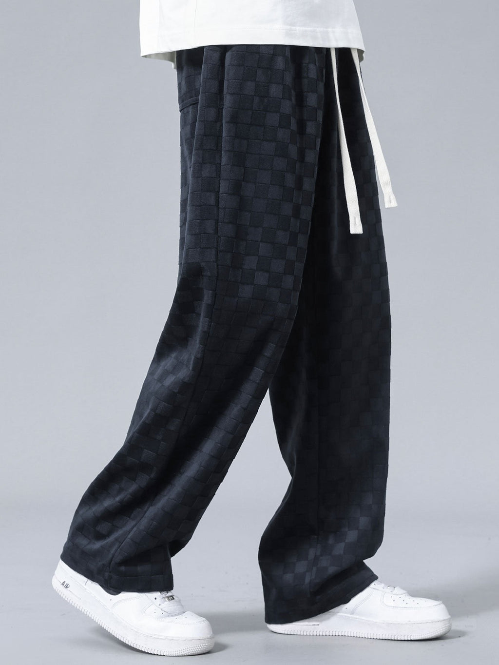 Pantalón recto oscuro con patrón damero, bolsillo lateral y dobladillo amplio.