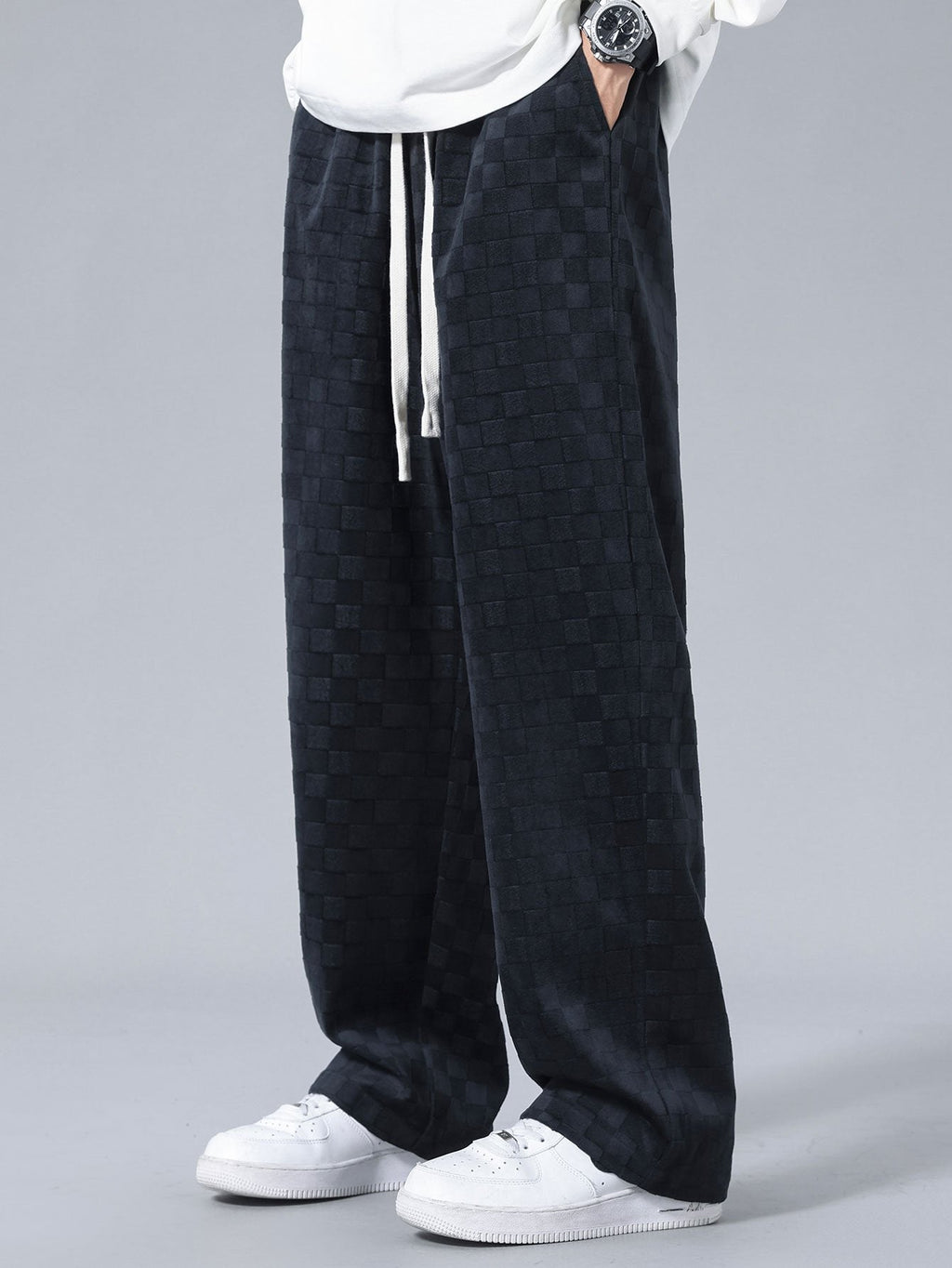 Pantalón recto oscuro con patrón damero, cordón blanco y corte holgado.