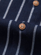 Camisa azul marino de rayas con botones marrones en la tapeta.