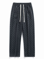 Pantalón recto oscuro con patrón damero, cintura elástica y cordón blanco.