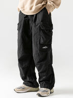 Pantalón paracaídas negro con bolsillos cargo laterales y etiqueta frontal