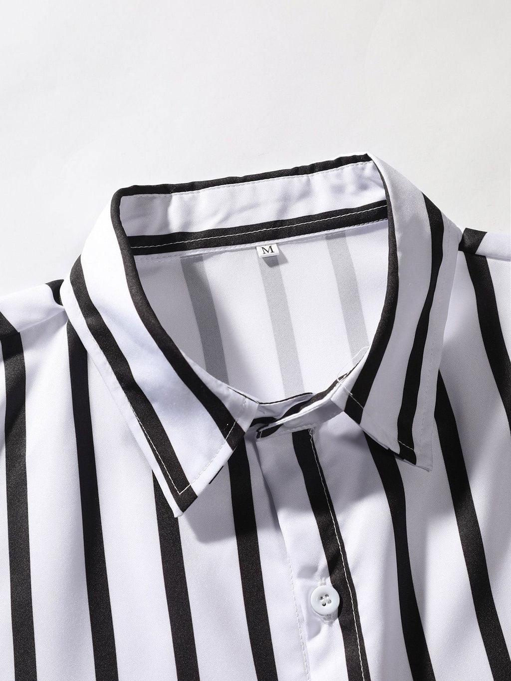 Camisa a rayas blancas y negras con cuello, botones y detalle de costura