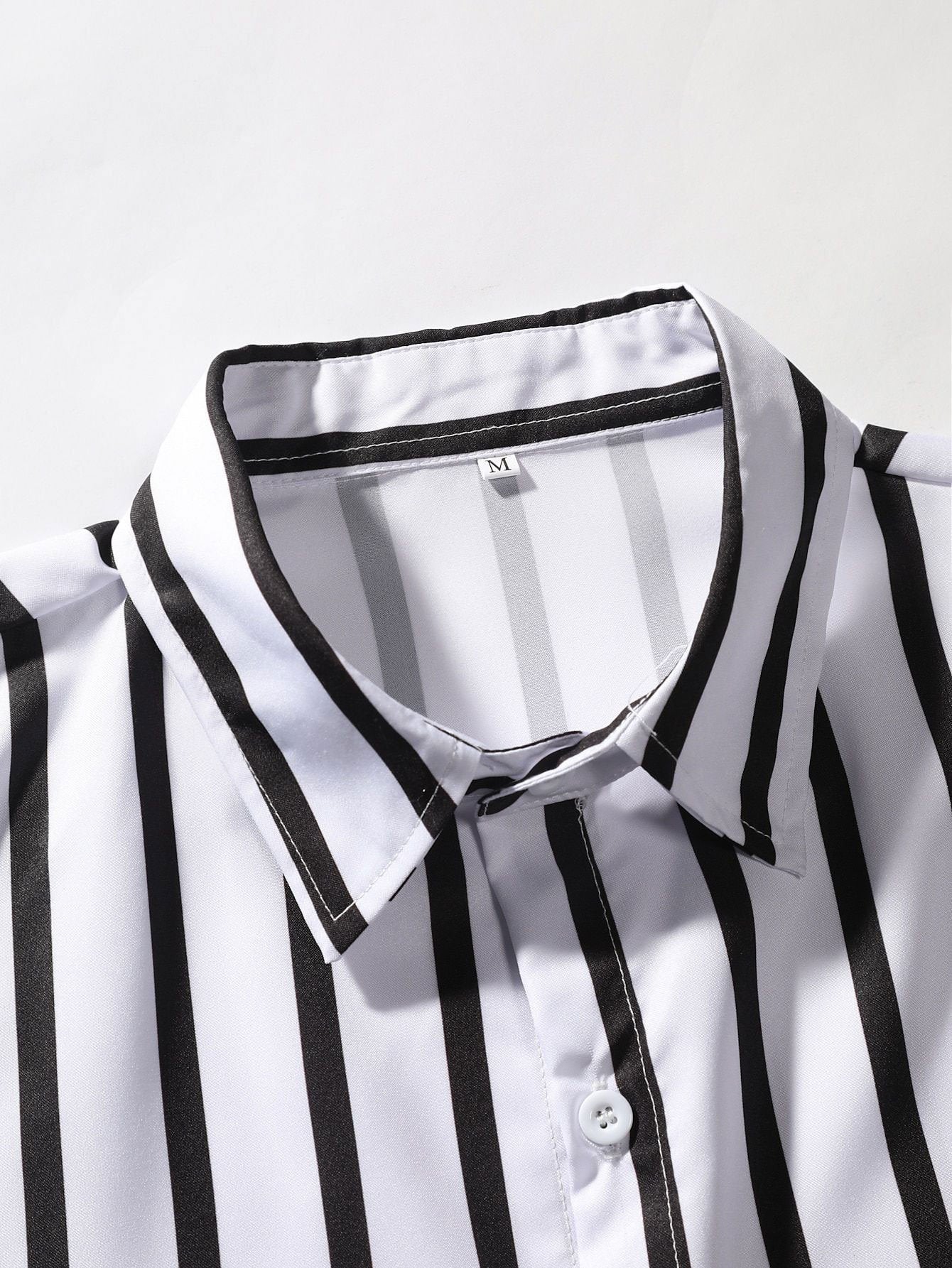 Camisa a rayas blancas y negras con cuello, botones y detalle de costura