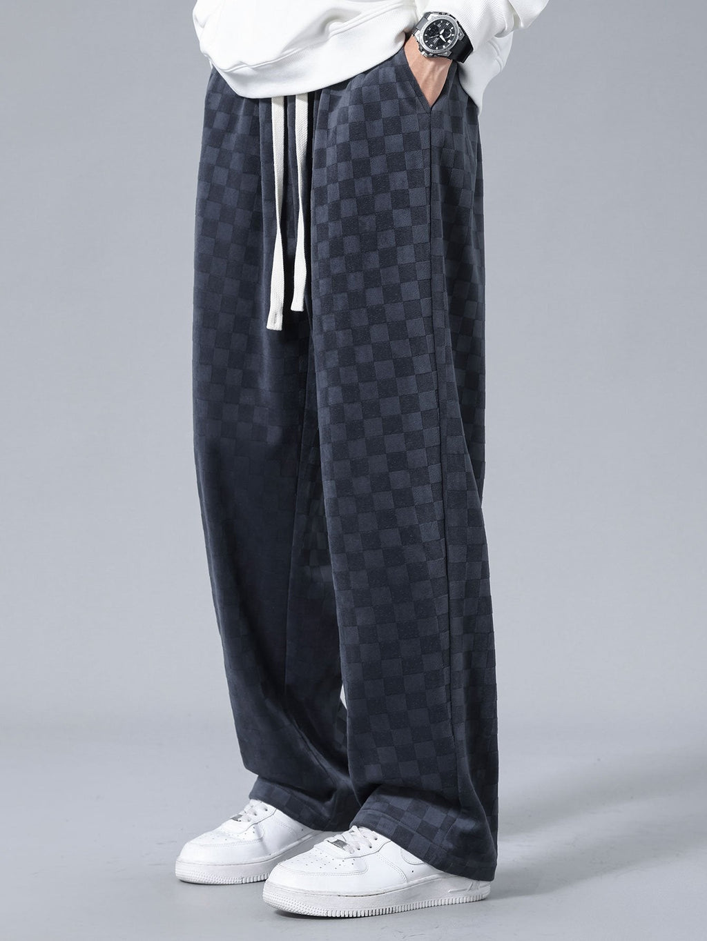 Pantalón recto oscuro con patrón damero, cordón blanco y caída amplia.