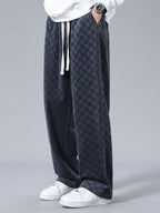 Pantalón recto oscuro con patrón damero, cordón blanco y caída amplia.