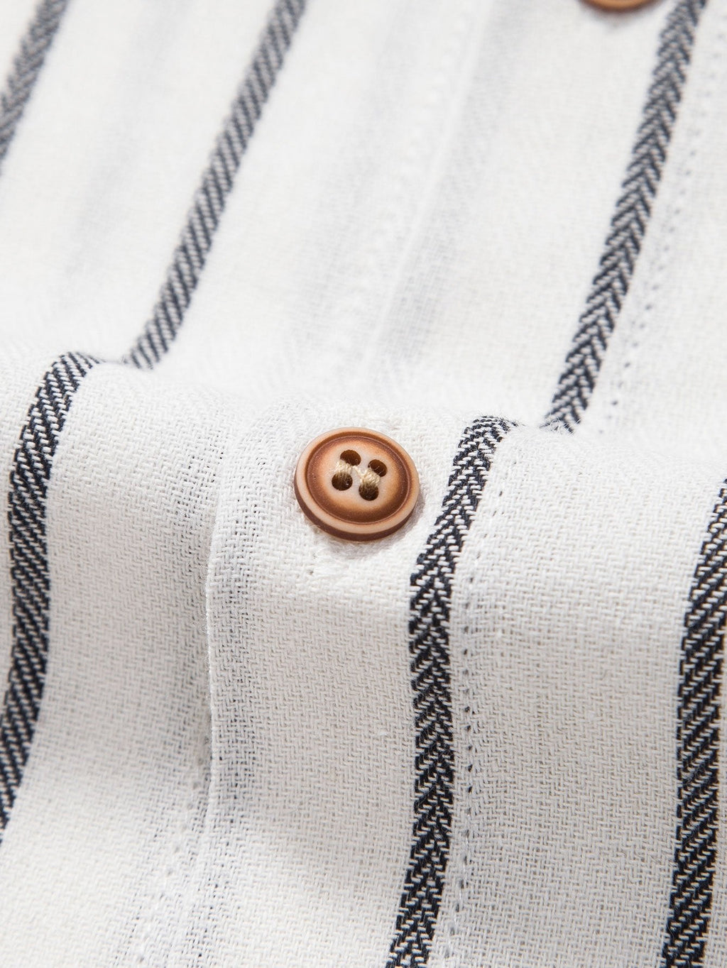Camisa blanca de rayas con botones marrones redondos en la tapeta.