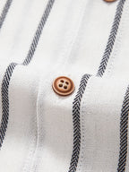Camisa blanca de rayas con botones marrones redondos en la tapeta.