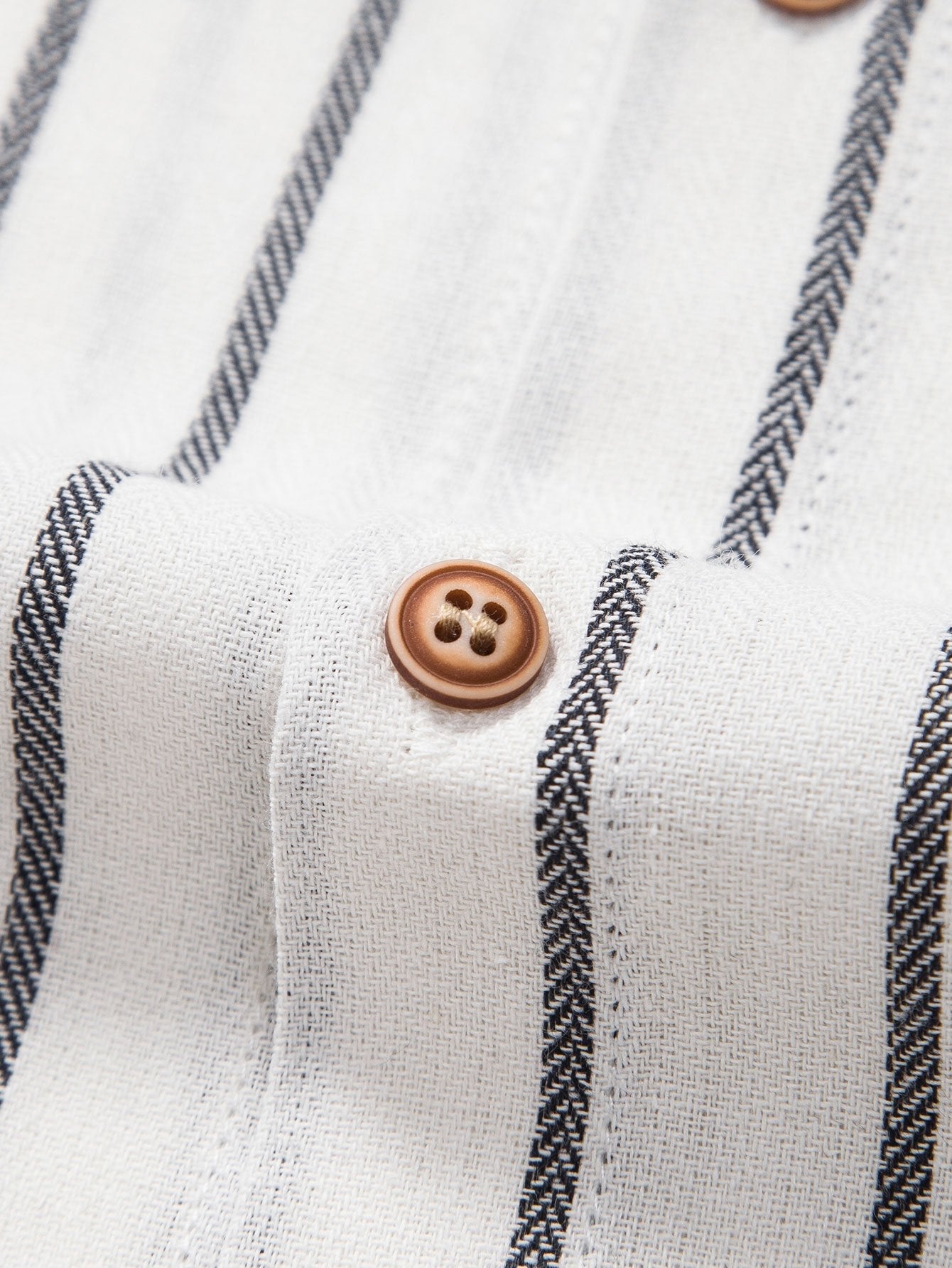 Camisa blanca de rayas con botones marrones redondos en la tapeta.