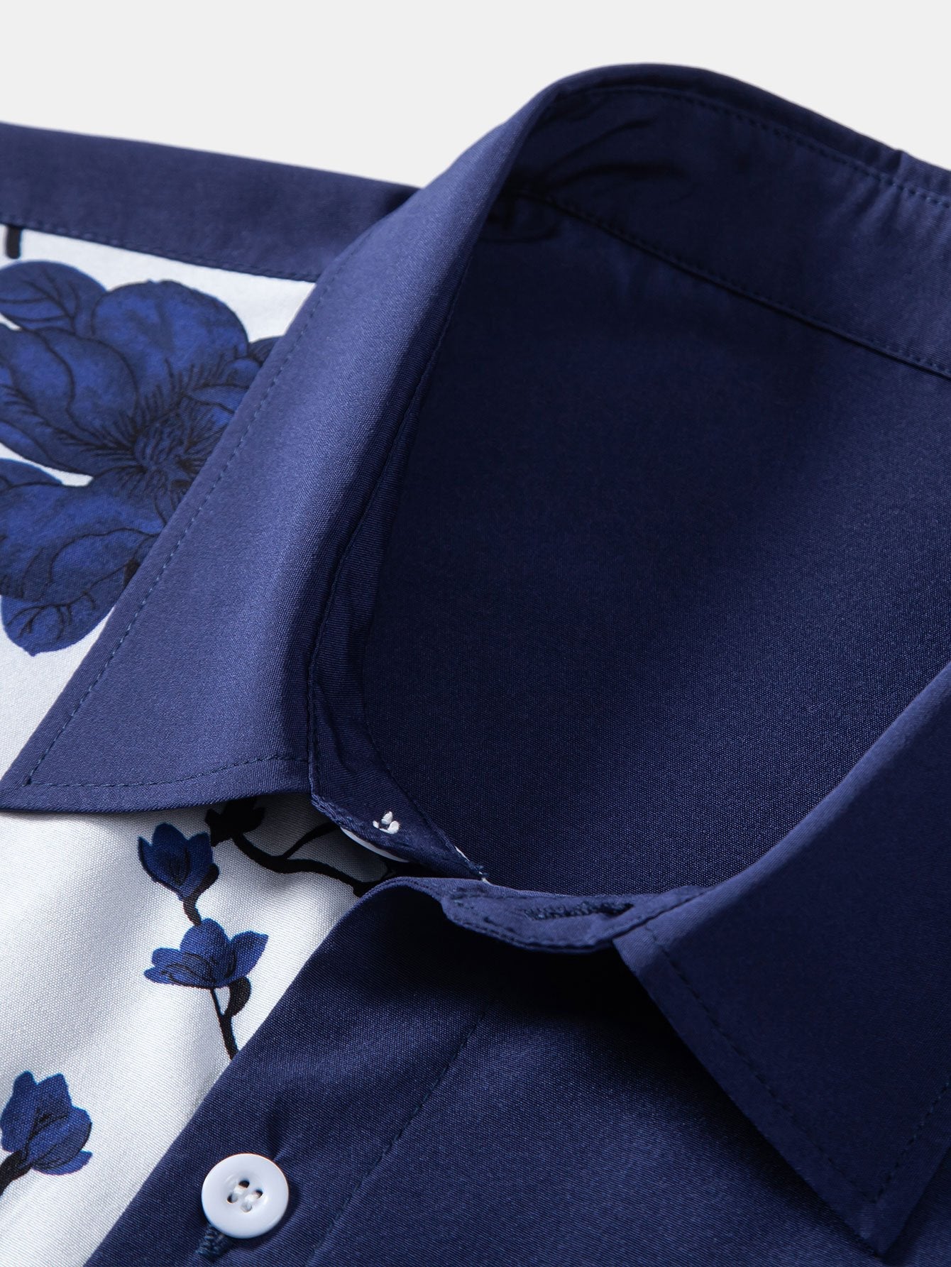 Cuello de camisa azul marino con botones y estampado floral azul sobre fondo blanco