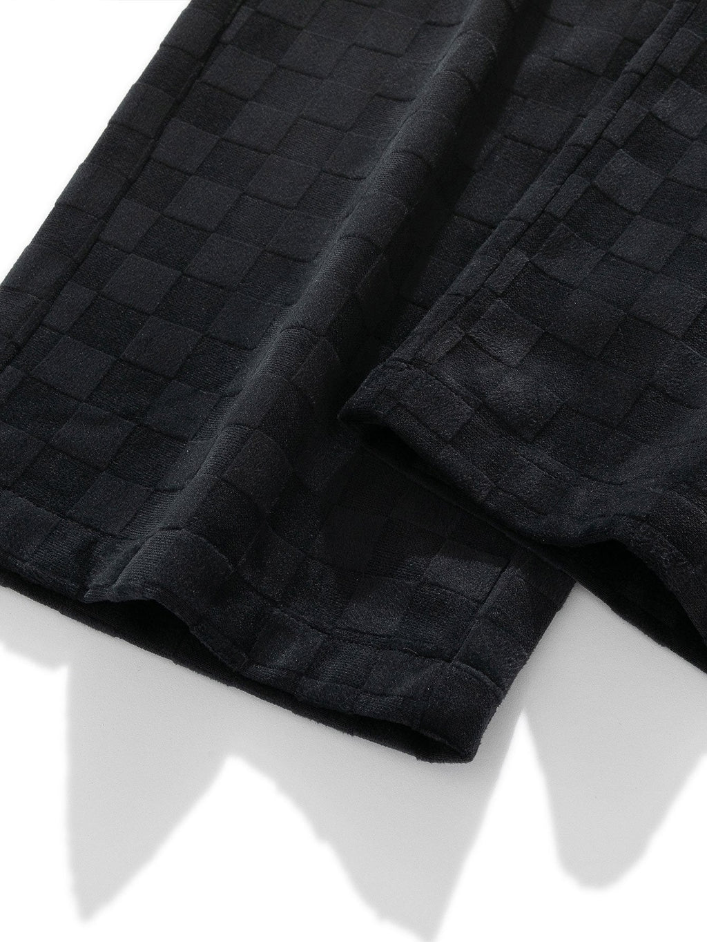 Pierna del pantalón recto con tejido cuadriculado negro y costuras visibles
