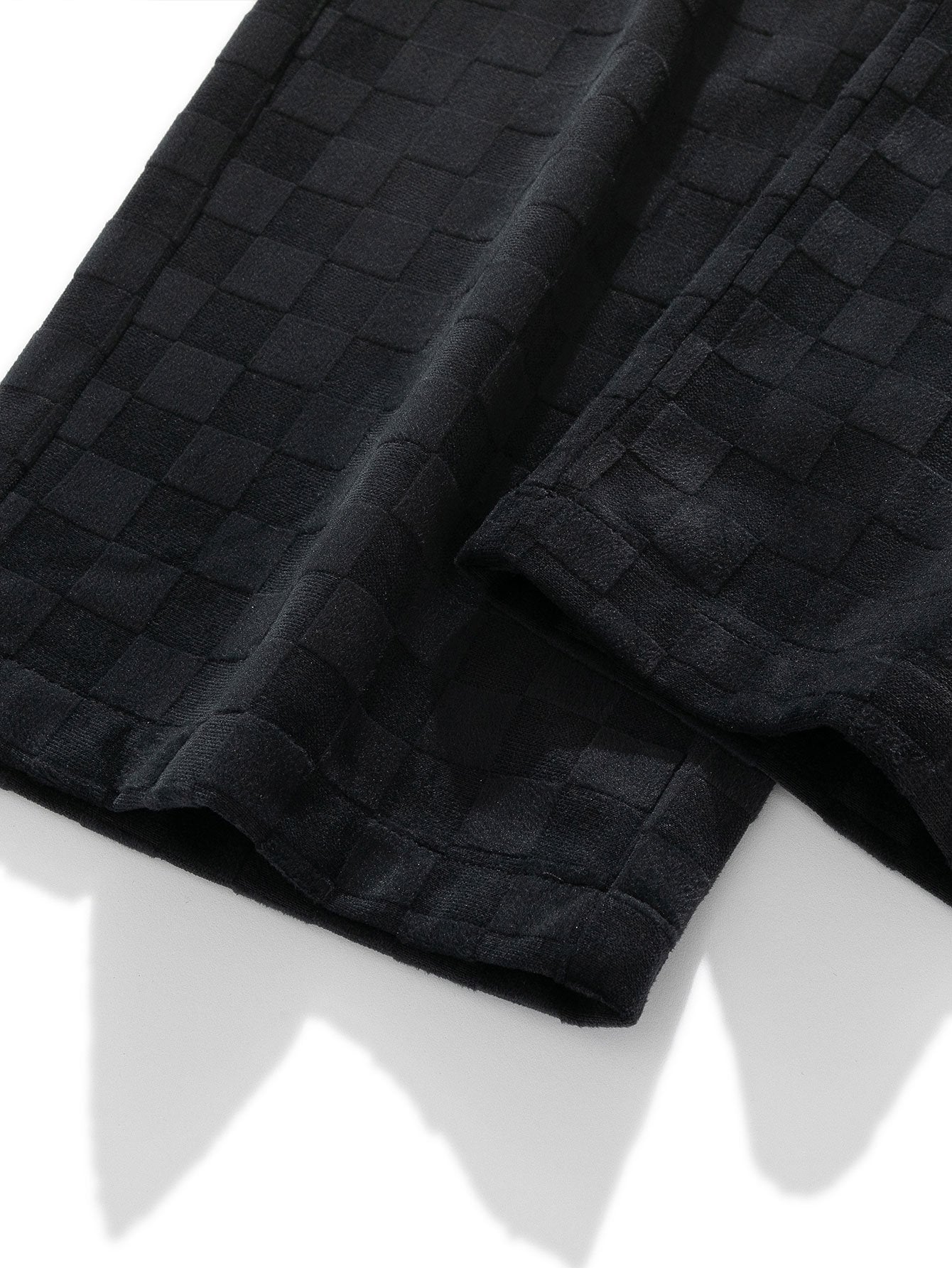 Pierna del pantalón recto con tejido cuadriculado negro y costuras visibles