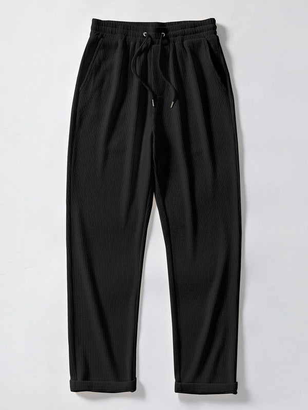 Pantalón recto de canalé negro, cintura elástica con cordón y bajo con puños.