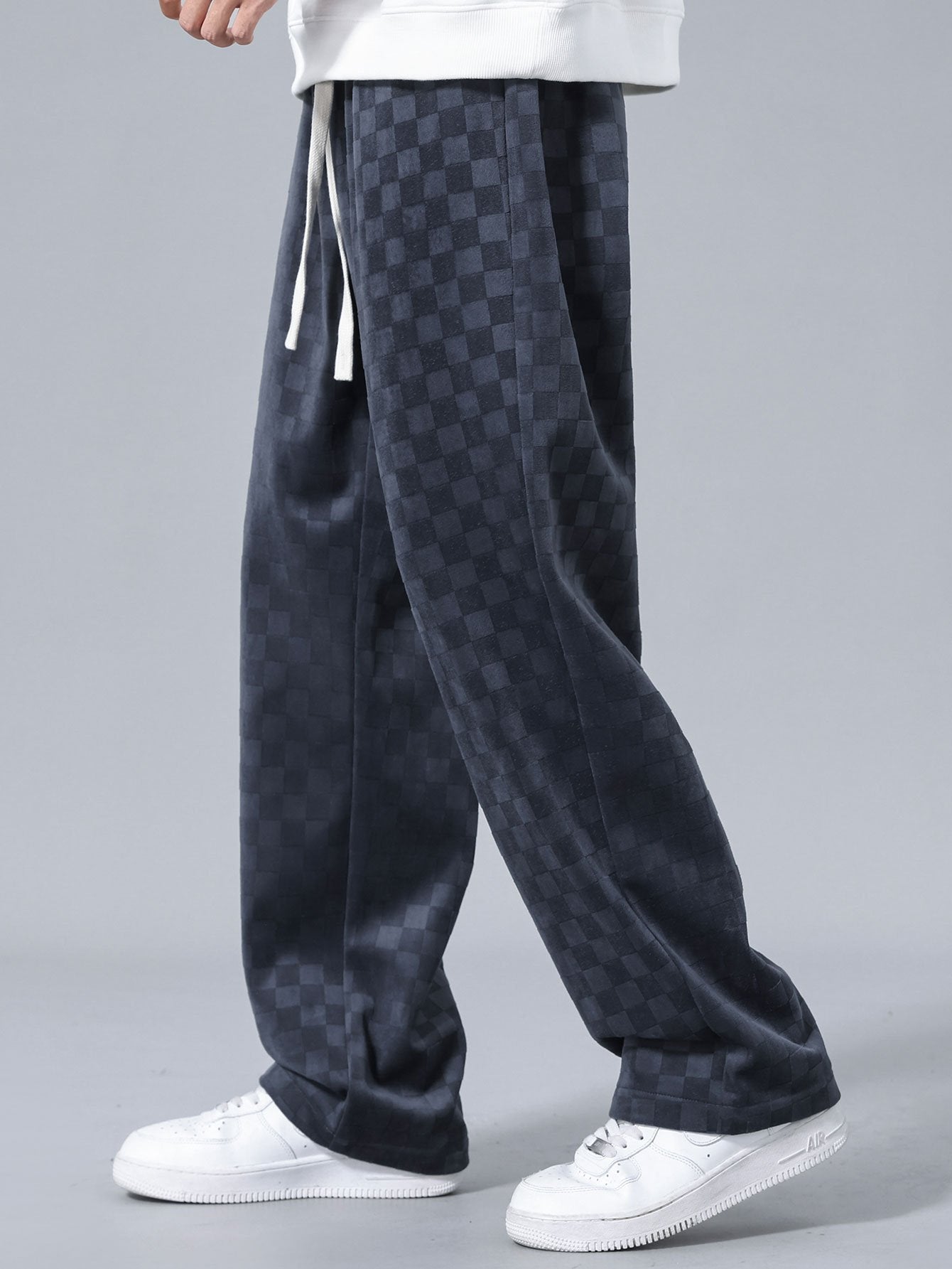 Pantalón recto oscuro con patrón damero, cordón en cintura y bolsillos laterales.