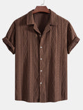 Camisa de manga corta café con solapa y botones al frente, tejido con relieve geométrico.