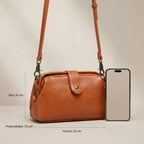 Bolso vintage de cuero naranja teja con correa larga y herrajes metálicos.