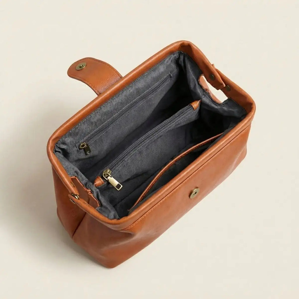 Bolso vintage de cuero marrón con interior gris y cierre frontal metálico abierto.