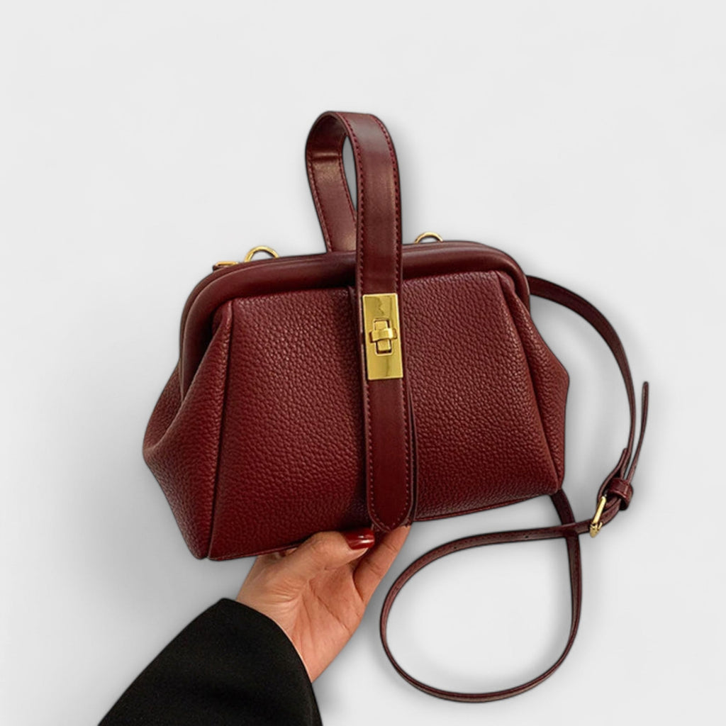 Bolso de cuero burdeos con asa alta, placa dorada y correa