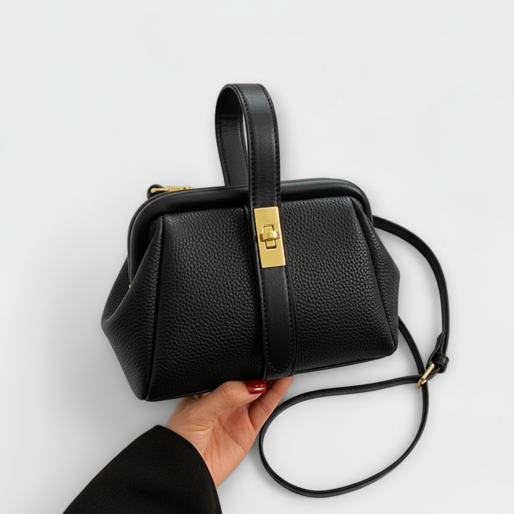 Bolso de cuero negro con placa dorada rectangular y bandolera